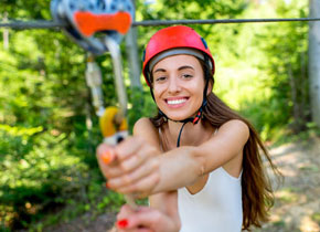 girl wearing a red helmet holding onto a carabiner to start ziplining